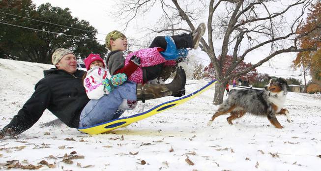 Getting air off of a ramp in Foster Park south of TCU, dad Landon Stallings rode with daughter Vada (age 9) and son Jack (age 8) as their dog "Halo" gives chase. Cold and ice remained in Fort Worth Sunday, with roads  especially treacherous in the the morning hours before temperatures rose, Sunday, Dec. 8, 2013. (AP Photo/Fort Worth Star-Telegram, Paul Moseley)